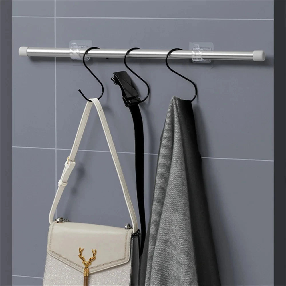 Silver self-adhesive curtain rod clips mounted on a gray wall, holding a black and gray towel.