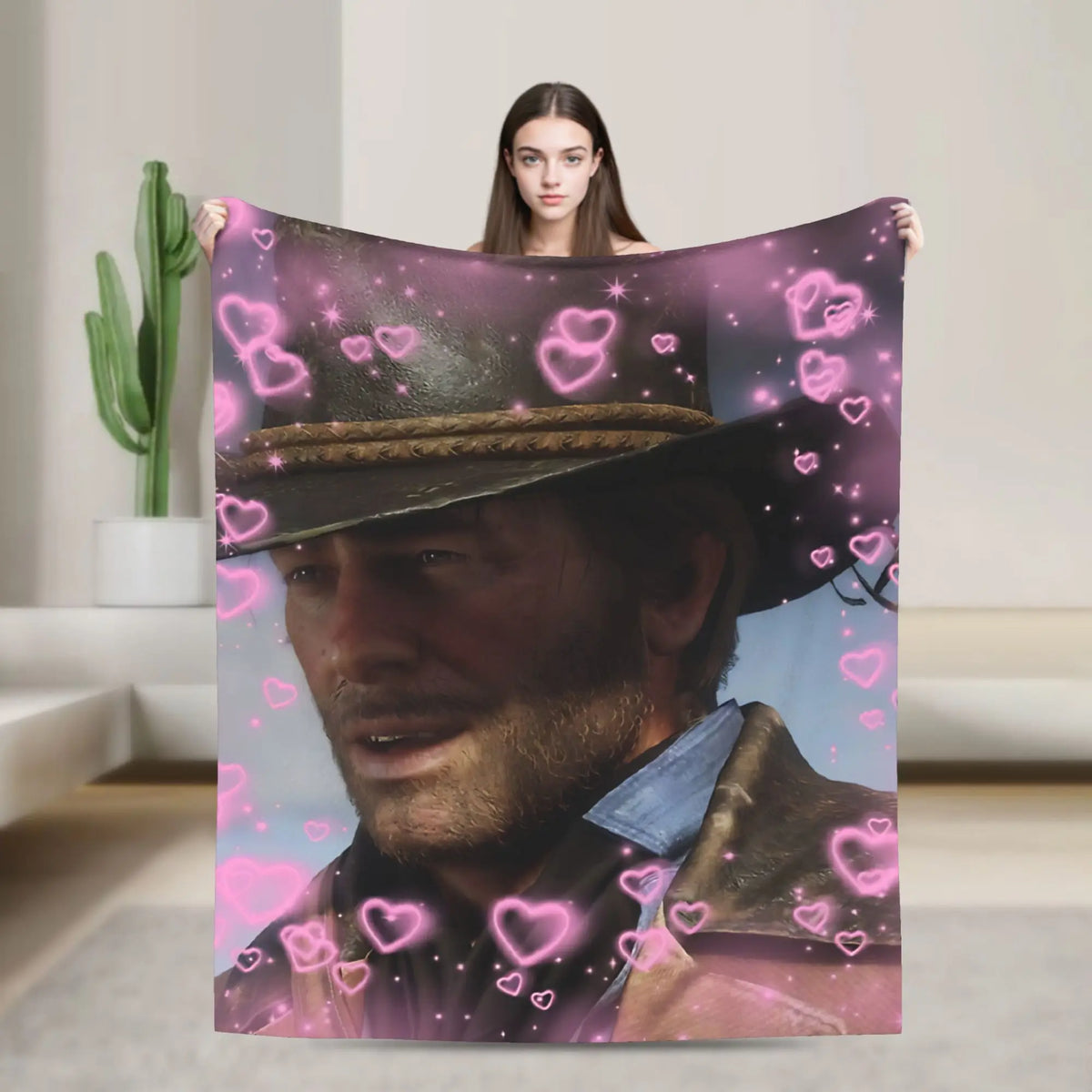 A person holds up a blanket featuring a portrait of a man in a hat surrounded by pink hearts.