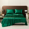 A luxurious emerald green satin flat bed sheet set with pillows and a draped sheet on a bed.