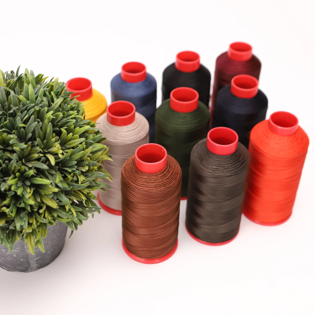 A collection of heavy duty nylon sewing thread spools in various colors including red, orange, green, blue, and black.