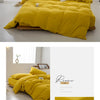 A bright yellow minimalist duvet cover displayed on a bed, with folded fabric samples nearby.