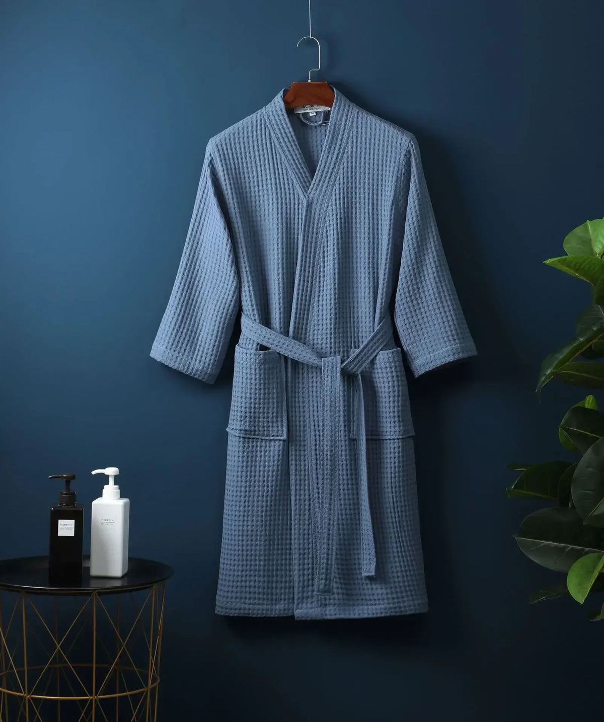 A light blue cotton terry robe hanging on a dark blue wall.