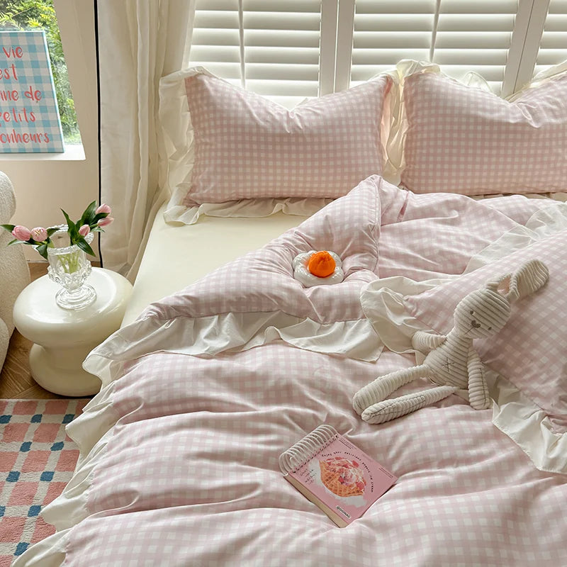 A pink gingham duvet cover set with matching pillows and a stuffed animal on a bed.