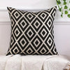 A black and cream diamond patterned chenille jacquard throw pillow on a white surface.