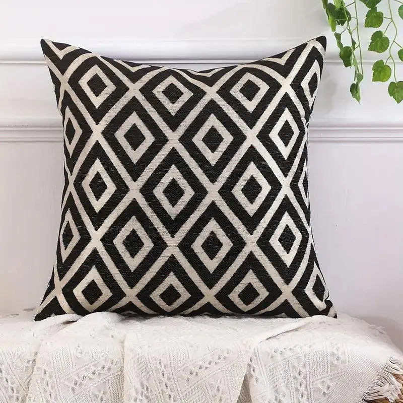 A black and cream diamond patterned chenille jacquard throw pillow on a white surface.