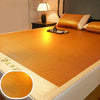 A close-up view of a golden orange natural bamboo cooling mat placed on a bed, with a lamp and decorative pillows nearby.
