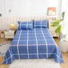 Blue plaid flat bed sheets with pink piping on a bed featuring a white headboard and natural light.