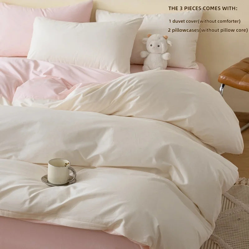 A set of soft pink and white bedding including a duvet cover, pillowcases, and a small stuffed animal.