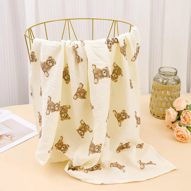 A cream-colored printable cotton crib sheet featuring small brown animal patterns draped over a gold wire hanger.