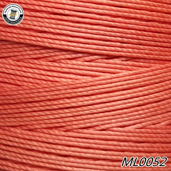 A close-up view of a spool of bright coral red waxed thread embroidery cord.