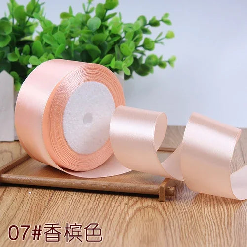 Roll of peach satin ribbon for gift wrapping and crafts displayed on a wooden surface.
