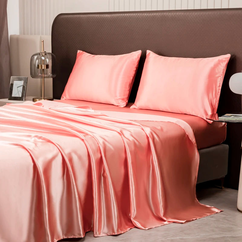 A luxury solid satin bedding set featuring pink sheets and pillows on a bed.