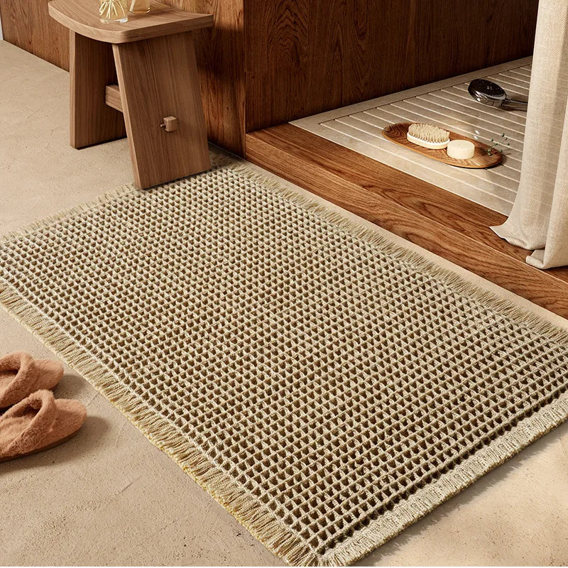 A beige waffle texture bath mat placed on a wooden floor next to a wooden cabinet.