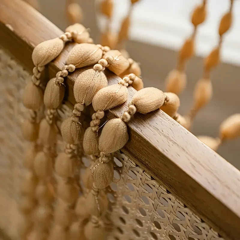 Close-up of a wooden door frame decorated with beige fabric tassels and fringe.