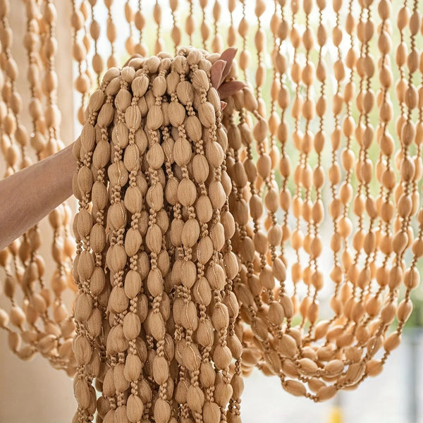 Close-up of a beige decorative fabric door curtain with a thick, braided tassel trim hanging.