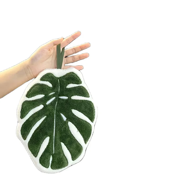A hand is holding a green leaf-shaped absorbent microfiber towel.
