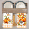 A set of two kitchen towels featuring a pumpkin and plaid design displayed in a wooden rack.