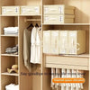 A wooden closet shelf displaying various fabric storage boxes for bedding and clothing.