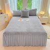 A gray plush bed skirt linen set is displayed on a bed with matching throw pillows and bedding.