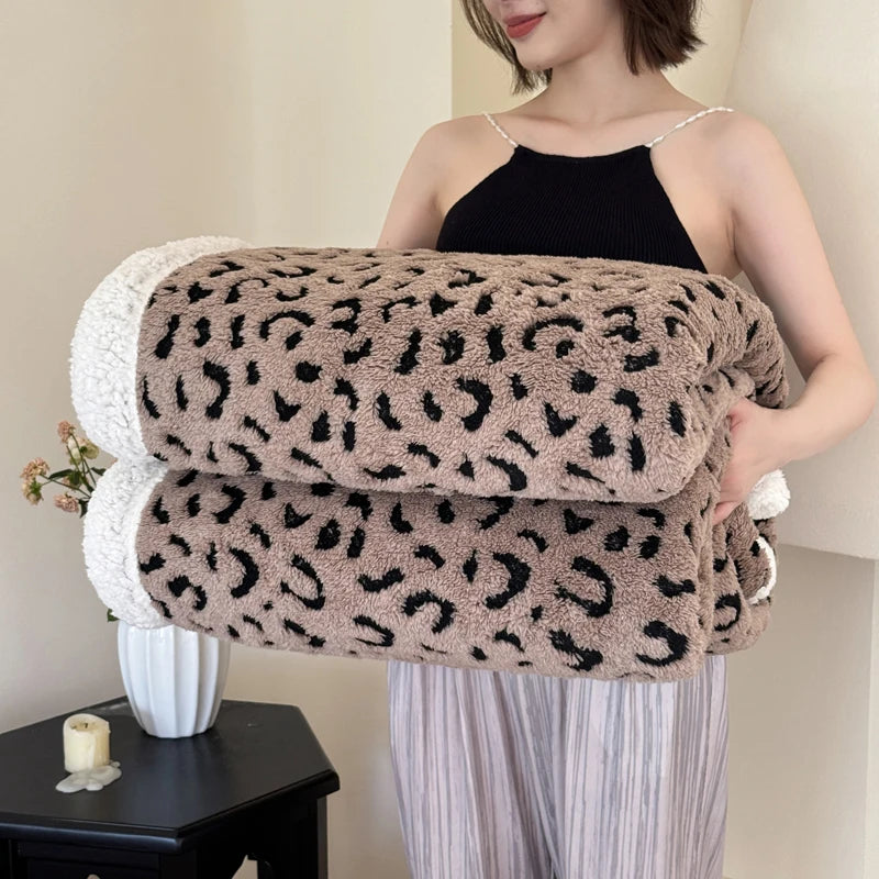 A woman models a brown leopard print knit throw blanket draped over her arm.