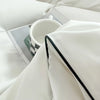 A white duvet cover set featuring a soft white duvet and matching pillow in bright natural light.