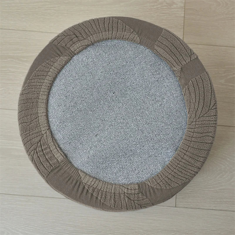 A round ottoman footrest slipcover in brown fabric with ribbed edges and a gray textured center.