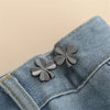 Silver clover-shaped button clips attached to a denim fabric
