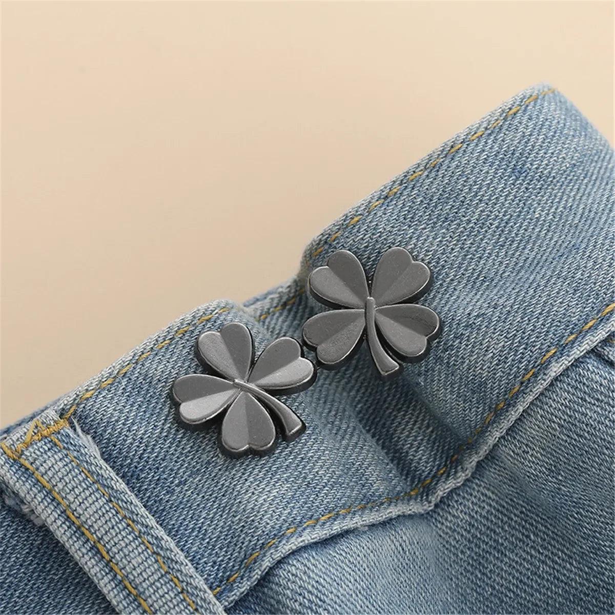 Silver clover-shaped button clips attached to a denim fabric