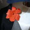 Orange rhinestone flower applique patch sewn onto a black garment.