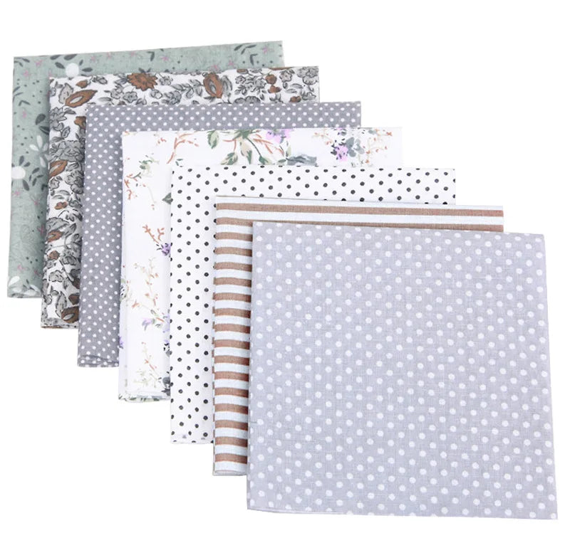 A stack of floral dot pattern cotton fabric squares in various muted green, gray, and white tones.