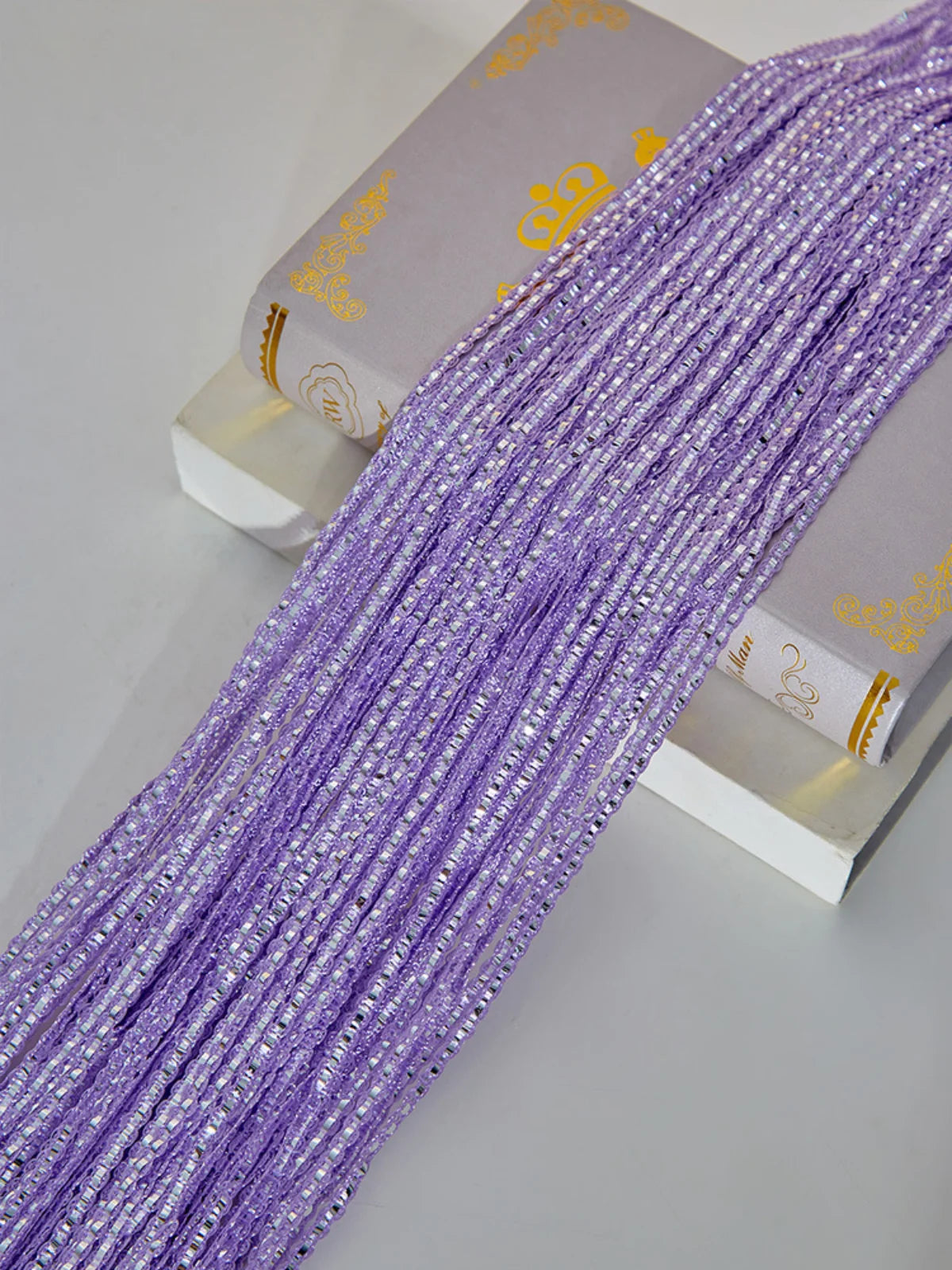 Purple decorative door string curtains for windows displayed next to a box.