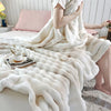 A person is wrapped in a fluffy white rabbit fur throw blanket on a bed.