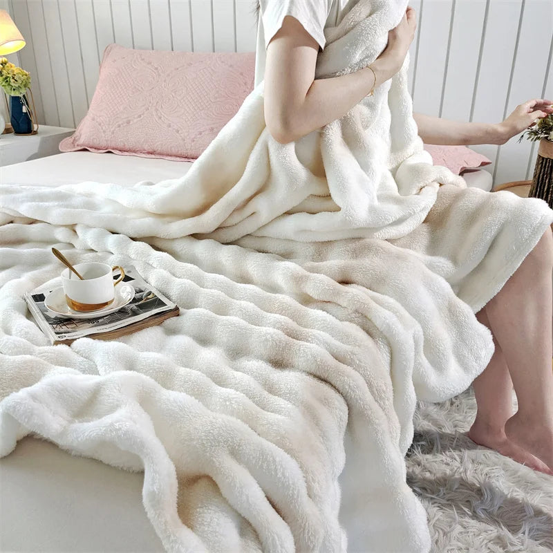 A person is wrapped in a fluffy white rabbit fur throw blanket on a bed.