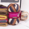 A ball of gradient dyed wool yarn in shades of brown, purple, and gray is shown next to a skein on a white background.