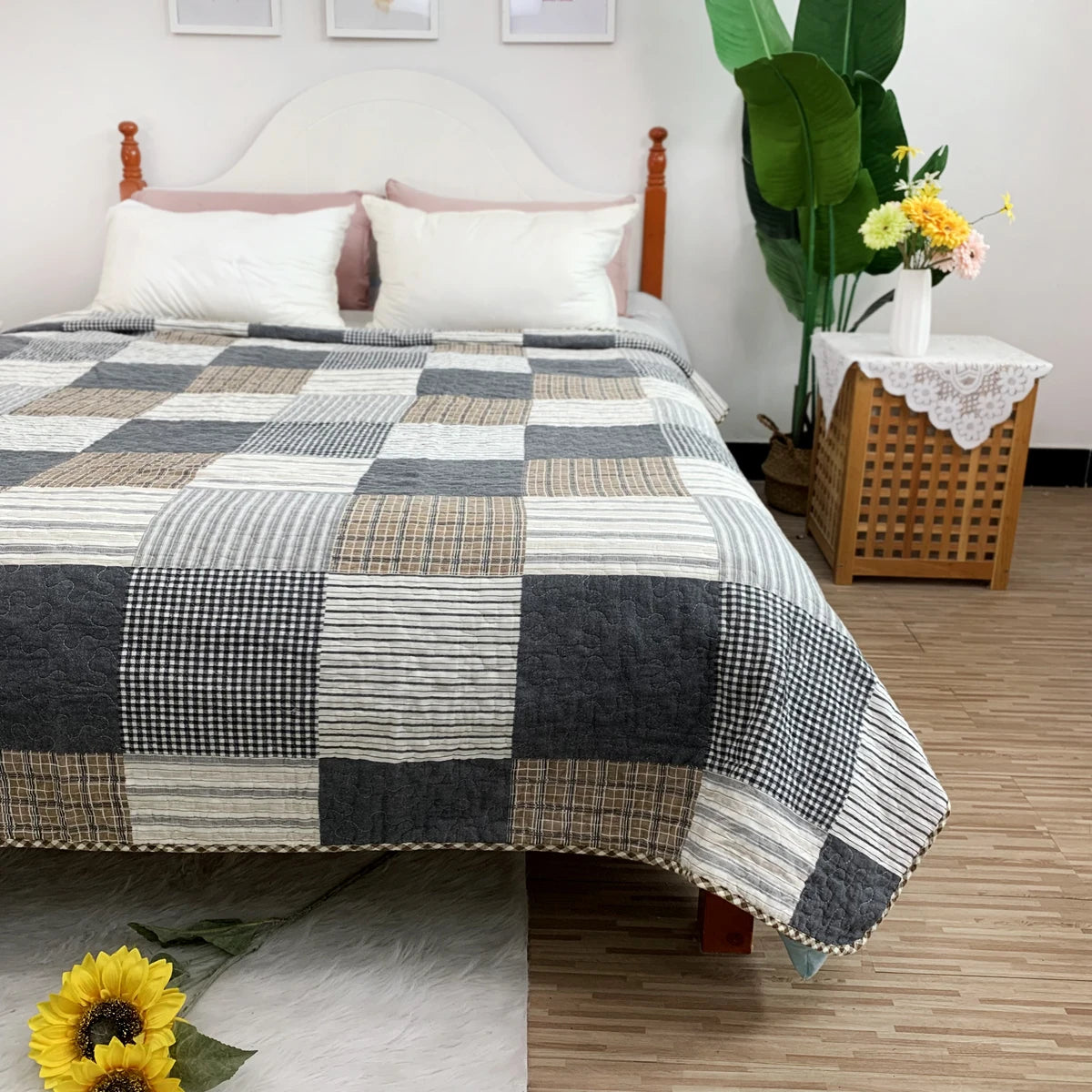 A gray and white checkered quilted bedspread is displayed on a bed with a white headboard and wooden nightstands.