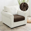 A white upholstered armchair with vertical stripes and a brown seat cover sits on a light wood floor.
