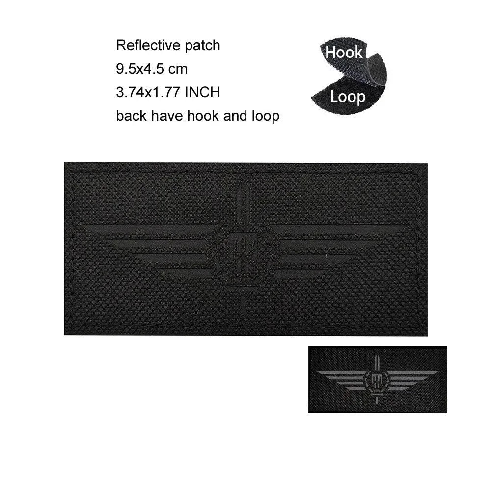 Black reflective patch featuring an embroidered eagle shield design with a hook and loop backing.