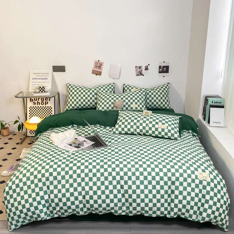 A green and white plaid duvet cover set displayed on a bed with a wooden nightstand and framed pictures.