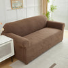A brown sofa slipcover featuring a jacquard leaves pattern placed in a bright room.