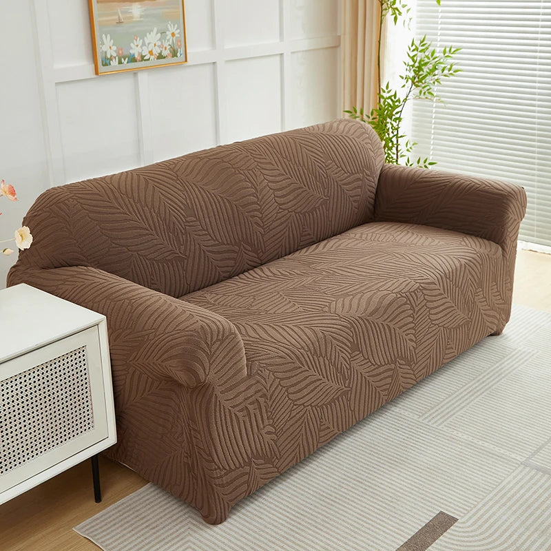 A brown sofa slipcover featuring a jacquard leaves pattern placed in a bright room.