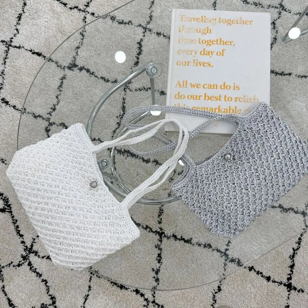 Two knitted face masks in white and gray resting on a glass with a quote card.