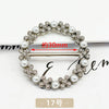 A silver-toned metal ring clip featuring small floral and pearl embellishments, shown with a measurement indicator.