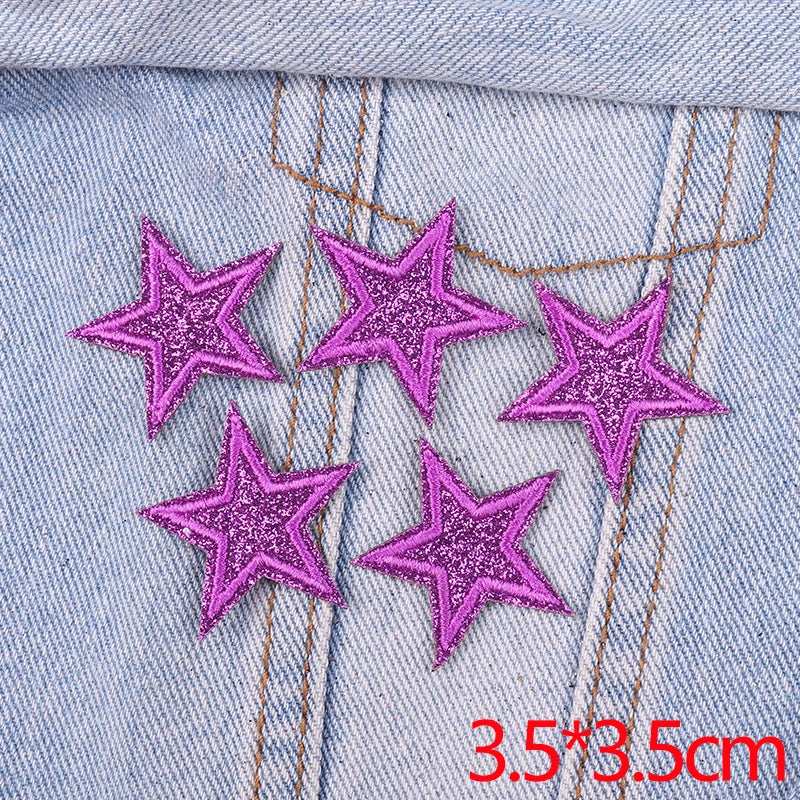 Five glitter pink star patches embroidered on light blue denim fabric