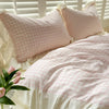 A pink and white checkered lace duvet cover set with matching pillows on a bed.
