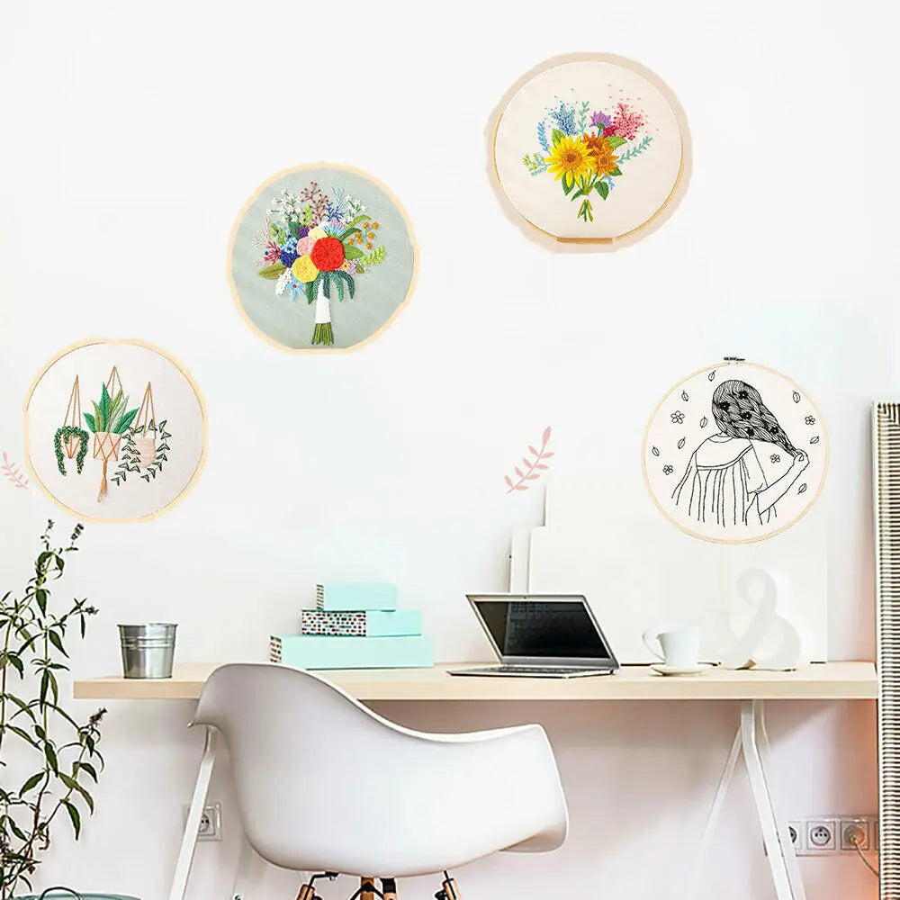 A collection of circular floral cross stitch embroidery designs displayed on a white wall above a wooden desk.