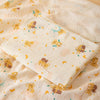 A soft double-layer cotton baby swaddle blanket with a light yellow background and small bear and moon patterns.