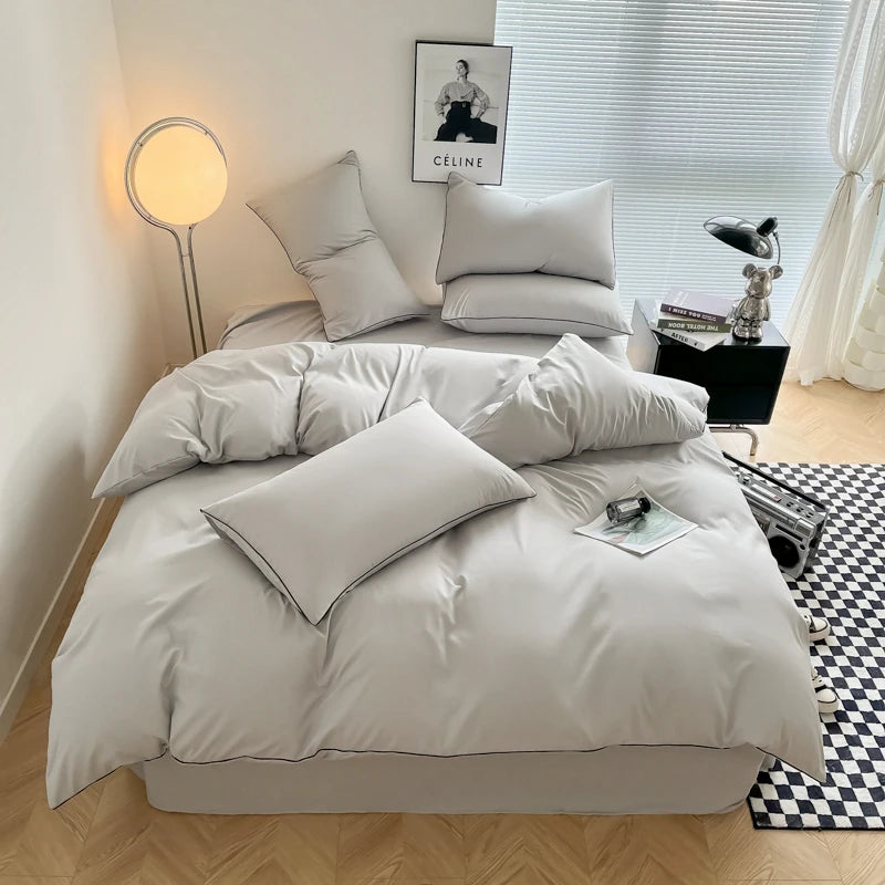A light gray duvet cover set displayed on a bed with pillows and a bedside lamp.