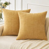Two mustard yellow chenille throw pillows resting on a light beige sofa.