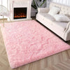 A fluffy pink tie-dyed plush floor mat placed in front of a white sofa and fireplace.