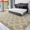 A beige geometric plush area rug is displayed in a modern bedroom setting.